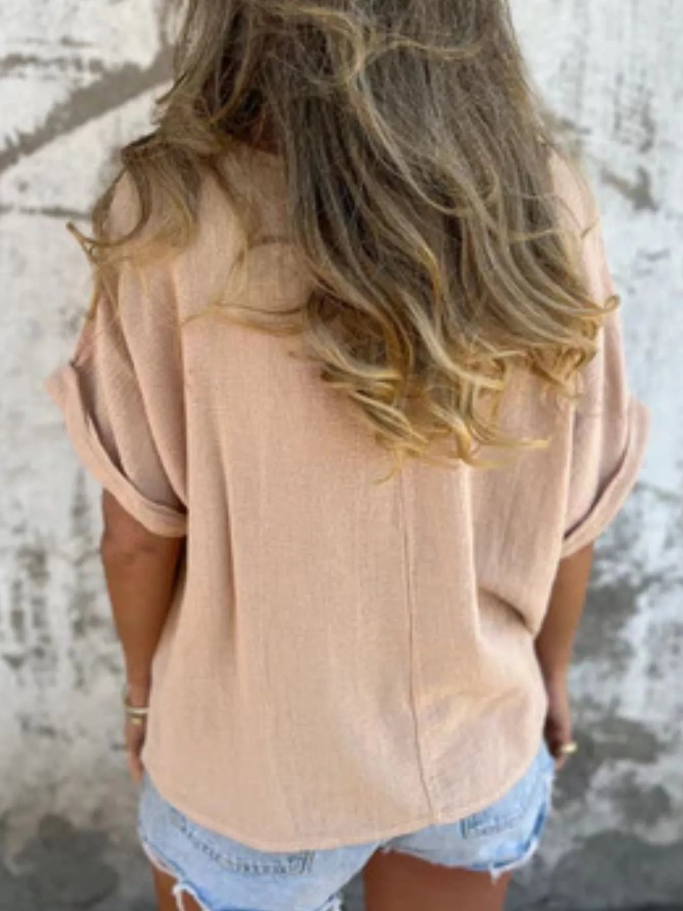 Back view of beige Women's Oversized Essential Tee highlighting its flowy fit and casual style, paired with shorts.