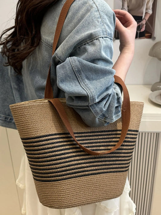 Striped woven medium size tote bag with black and tan stripes, worn over shoulder with casual denim outfit. Ideal for everyday use.