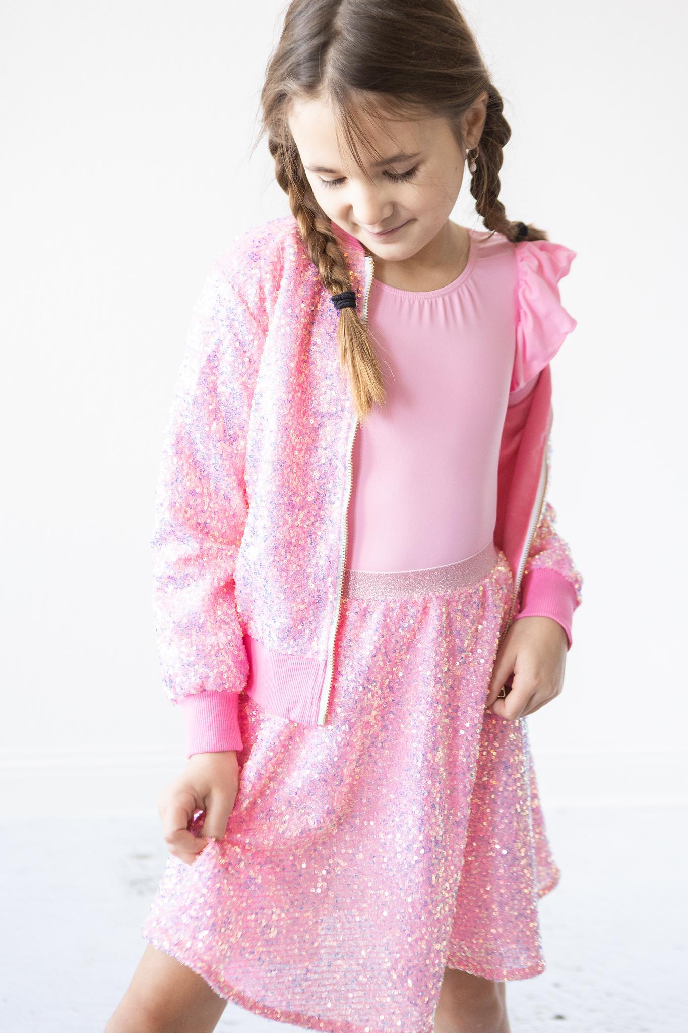 Young girl wearing a pink outfit with a matching jacket on a white background