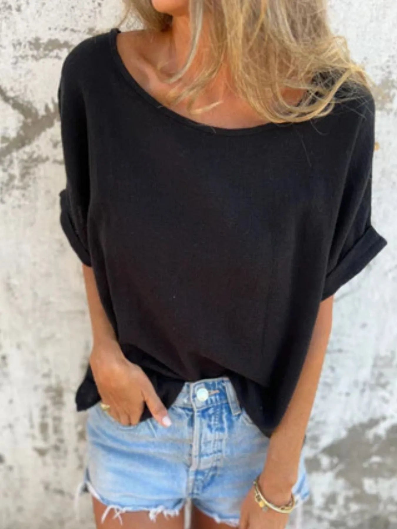 Black Women's Oversized Essential Tee styled with rolled sleeves and tucked into light denim shorts for a chic casual outfit.