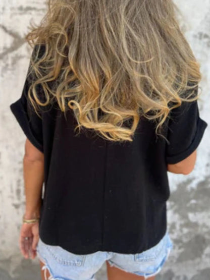 Back view of black Women's Oversized Essential Tee showcasing its relaxed drape and soft fabric, paired with denim shorts.
