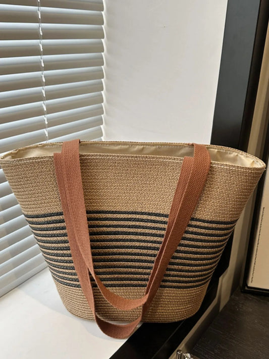 Medium-sized striped woven tote bag in black and tan with brown handles, displayed upright near window. Eco-friendly shopper bag.