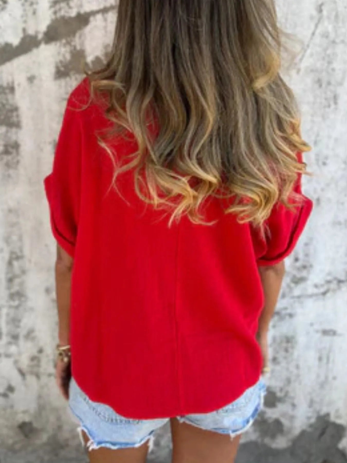 Back view of red Women's Oversized Essential Tee highlighting its relaxed drape and soft fabric, paired with denim shorts.