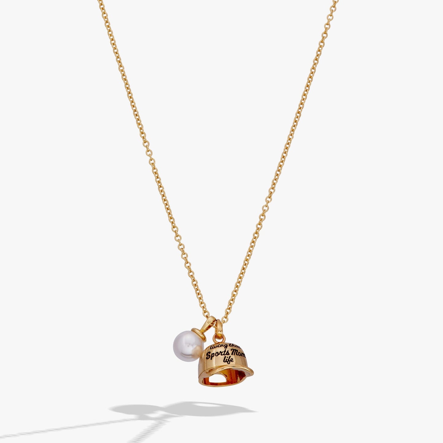 Gold necklace with a bell and pearl pendant on a white background