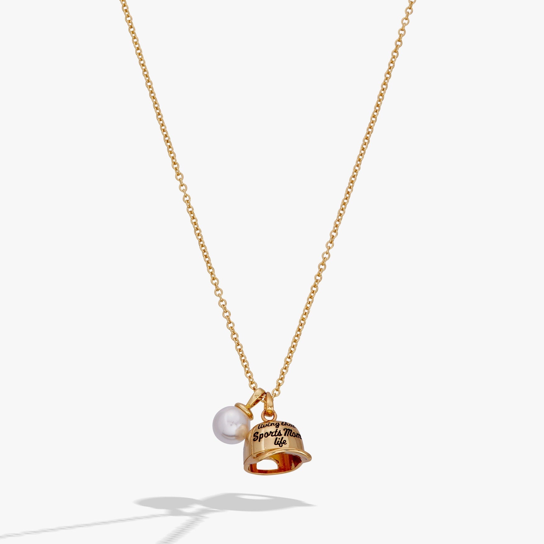 Gold necklace with a bell and pearl pendant on a white background