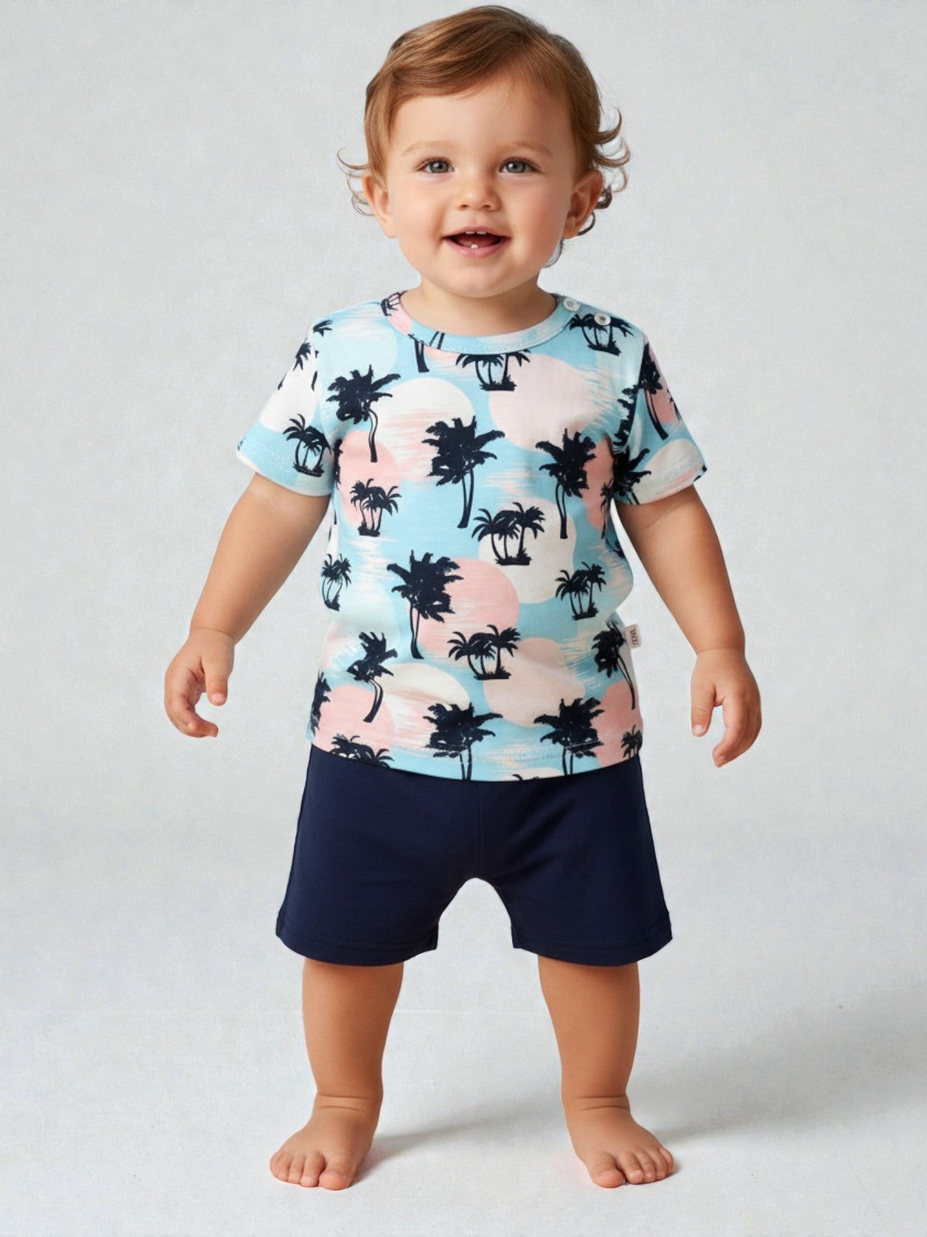 Child wearing a colorful palm tree shirt and navy shorts on a plain background